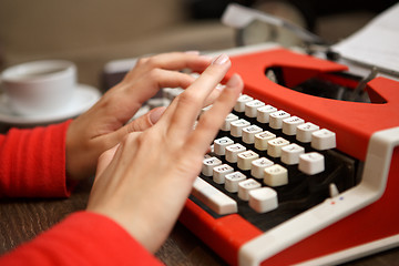 Image showing human hands writing on red typewriter