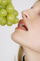 Image showing Young woman eating grapes