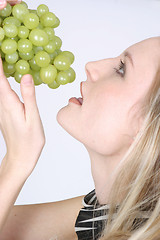 Image showing Young woman eating grapes
