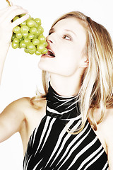 Image showing Young woman eating grapes