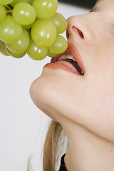 Image showing Young woman eating grapes