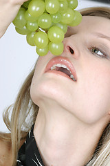 Image showing Young woman eating grapes