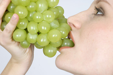 Image showing Young woman eating grapes