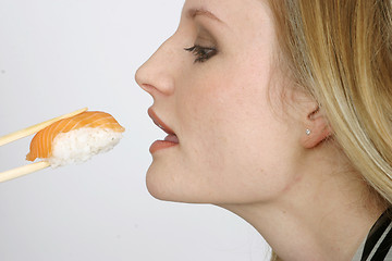 Image showing Young woman eating sushi