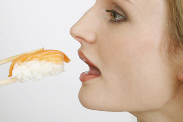 Image showing Young woman eating sushi