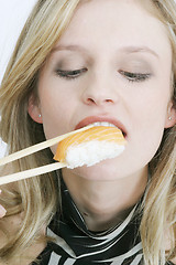 Image showing Young woman eating sushi