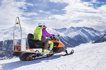 Image showing Young couple riding snowmobile snow mountain road