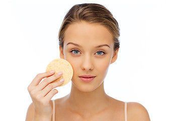 Image showing young woman cleaning face with exfoliating sponge