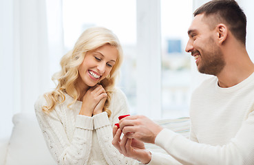 Image showing happy man giving engagement ring to woman at home