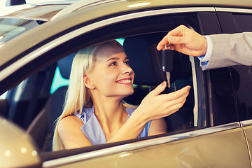 Image showing happy woman getting car key in auto show or salon