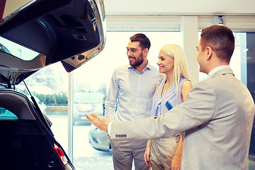 Image showing happy couple with car dealer in auto show or salon