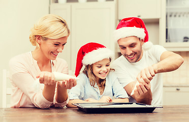 Image showing happy family in santa helper hats making cookies