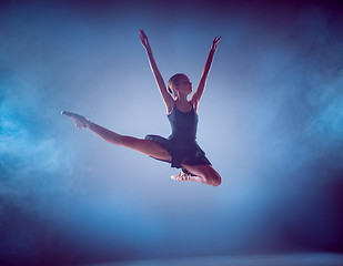 Image showing The silhouette of young ballet dancer jumping on a blue background.