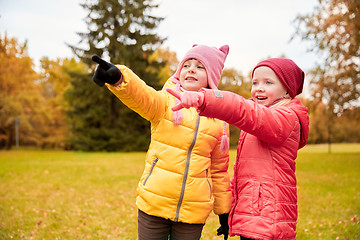 Image showing happy little girls pointing finger in autumn park