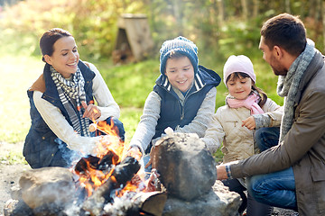 Image showing happy family roasting marshmallow over campfire