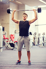 Image showing young man flexing muscles with barbell in gym