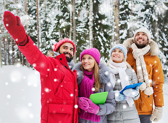 Image showing smiling friends with tablet pc in winter forest