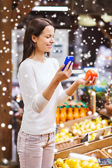 Image showing happy woman with smartphone and tomato in market