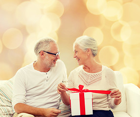 Image showing happy senior couple with gift box at home