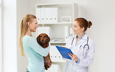 Image showing happy woman with dog and doctor at vet clinic