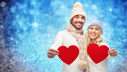 Image showing smiling couple in winter clothes with red hearts