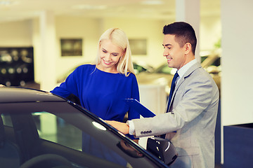 Image showing happy woman with car dealer in auto show or salon