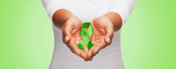 Image showing close up of hands holding green awareness ribbon