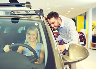 Image showing happy couple buying car in auto show or salon