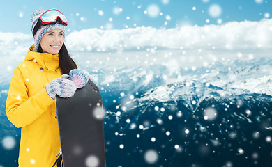 Image showing happy young woman with snowboard over mountains