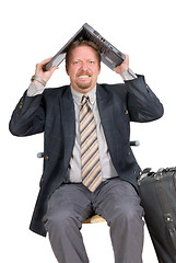 Image showing Traveling businessman hiding under laptop