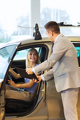 Image showing happy woman with car dealer in auto show or salon