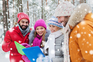 Image showing smiling friends with tablet pc in winter forest