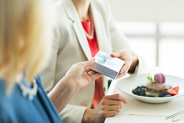 Image showing close up of women giving present at restaurant