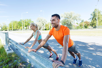 Image showing close up of happy couple doing push-ups outdoors