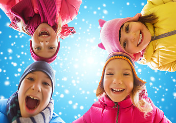 Image showing happy little children faces over blue sky and snow