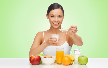 Image showing happy woman eating yogurt for breakfast