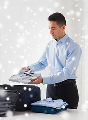 Image showing businessman packing clothes into travel bag