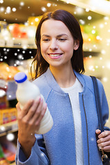 Image showing happy woman holding milk bottle in market