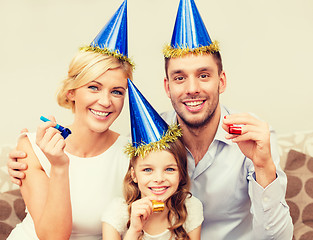 Image showing smiling family in blue hats blowing favor horns