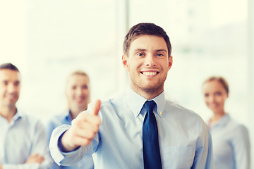 Image showing smiling businessman showing thumbs up in office