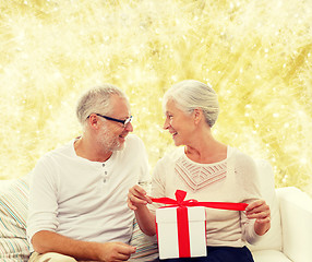 Image showing happy senior couple with gift box at home