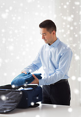 Image showing businessman packing clothes into travel bag