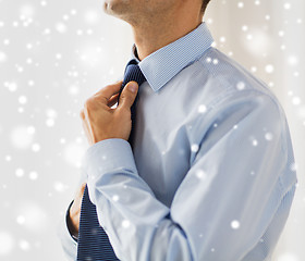 Image showing close up of man in shirt adjusting tie on neck