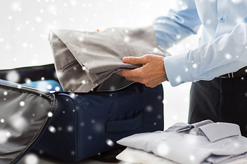 Image showing businessman packing clothes into travel bag