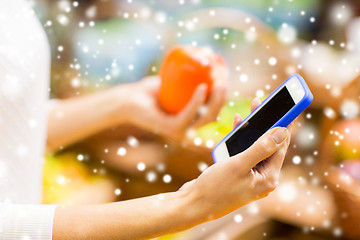 Image showing woman with smartphone and persimmon in market