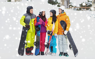 Image showing happy friends in helmets with snowboards talking