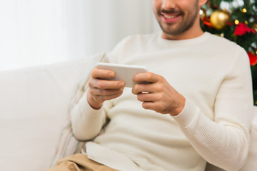 Image showing smiling man with smartphone at home for christmas