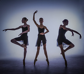 Image showing The silhouettes of young ballet dancers posing on a gray background.