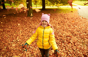 Image showing happy girl playing with autumn leaves in park