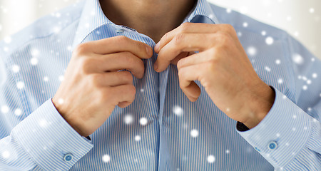 Image showing close up of man fastening button on shirt